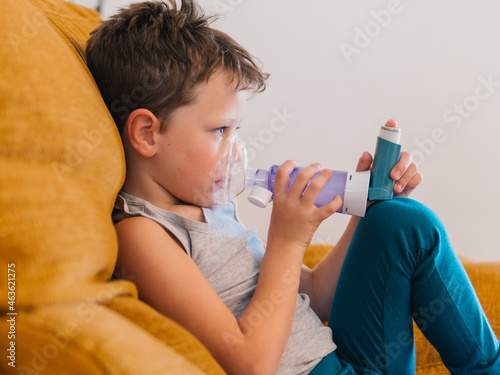 Ill child breathing in respirator with inhaler photo