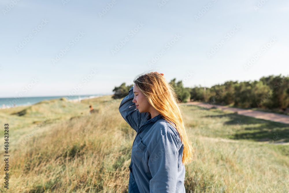 Pensive woman standing in grassy meadow