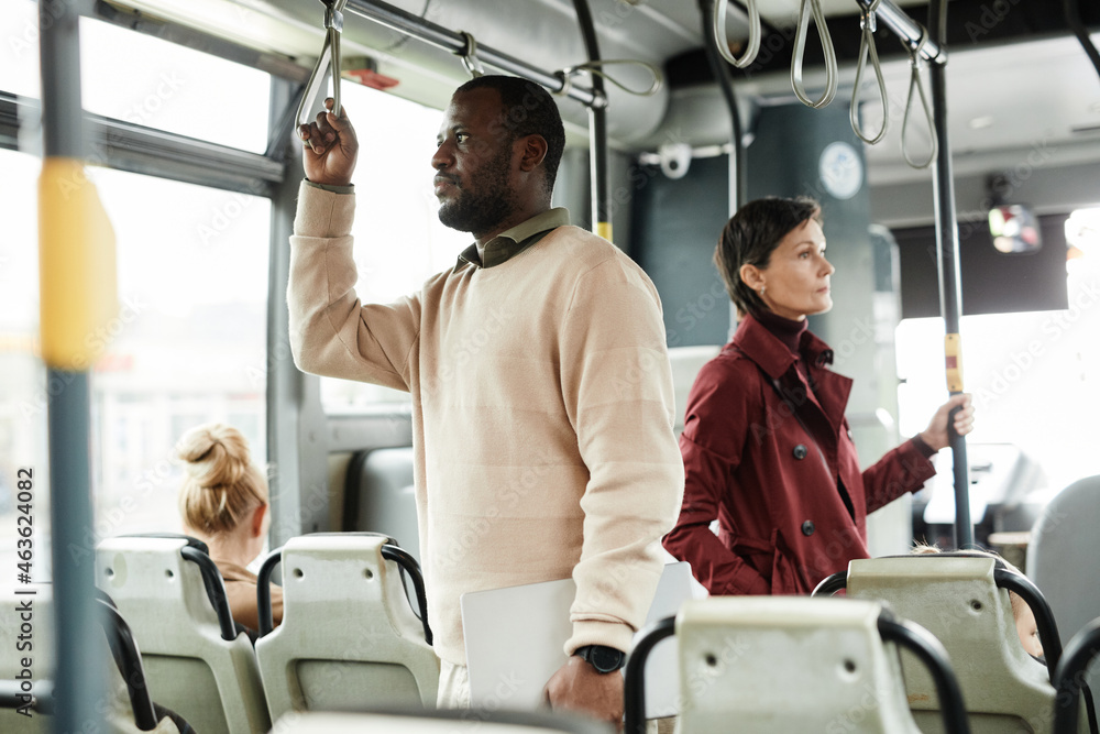 Side view portrait of African-American man holding onto railing in bus while traveling by public transport in city, copy space Side view portrait of African-American man holding onto railing in bus while traveling by public transport in city, copy space