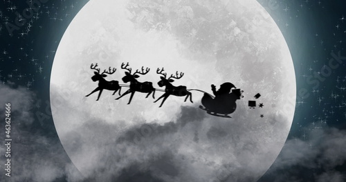 Canvas Print Silhouette of Santa Claus in sleigh being pulled by reindeers against moon
