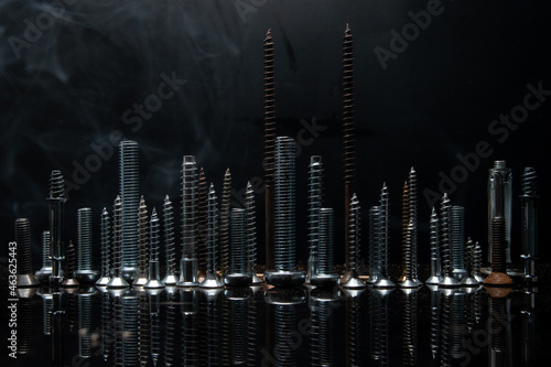 Skyline with various screws and bolts on a reflective surface in the dark background
