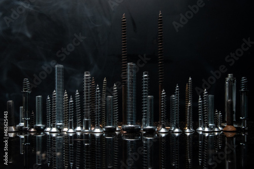 Картината върху платно Skyline with various screws and bolts on a reflective surface in the dark backgr