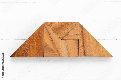 Wood tangram puzzle in trapezium shape on white wood background photo