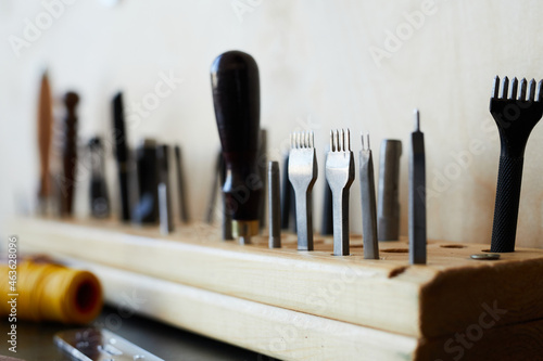 Extreme close up of leathermaking tools on rack in tanners workshop, copy space photo