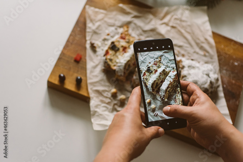 Baker takes a photo of the baked Christmas stollen, on a mobile phone