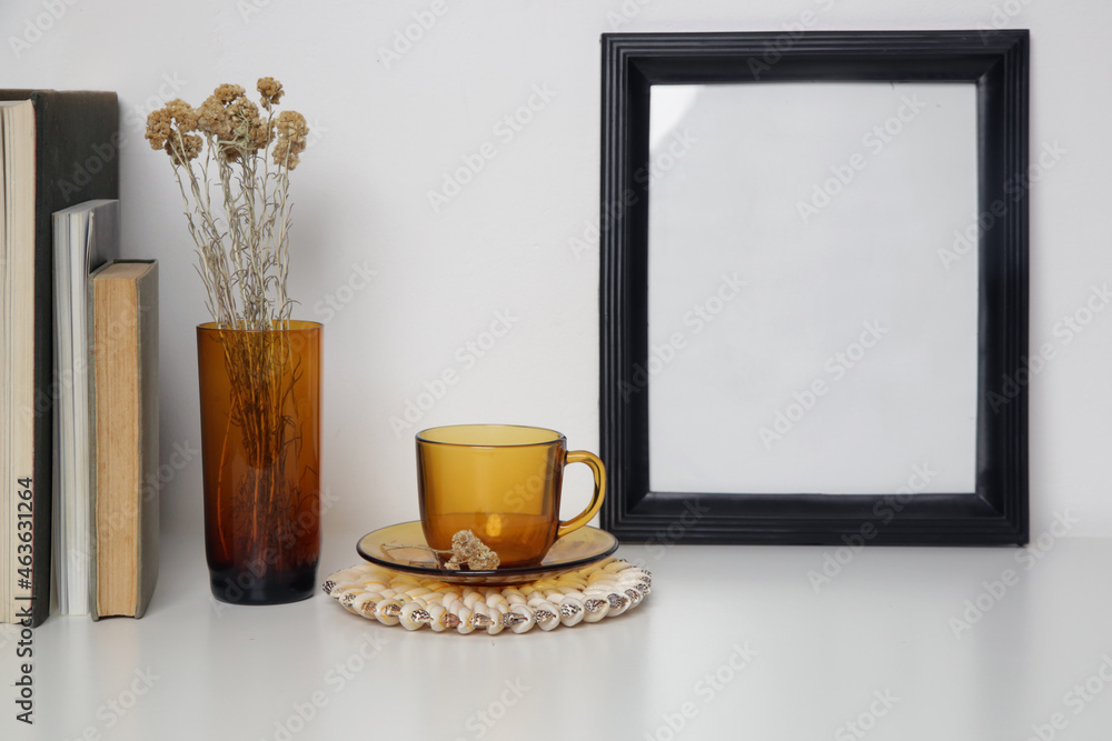 Wooden frame mockup on table with home interior decor elements. White wall background. Wooden frame mockup on table with home interior decor elements. White wall background.