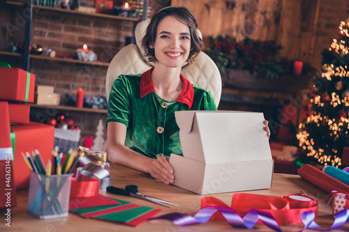 Portrait of attractive cheery girl elf opening box packing dream december day at home modern loft industrial interior indoors