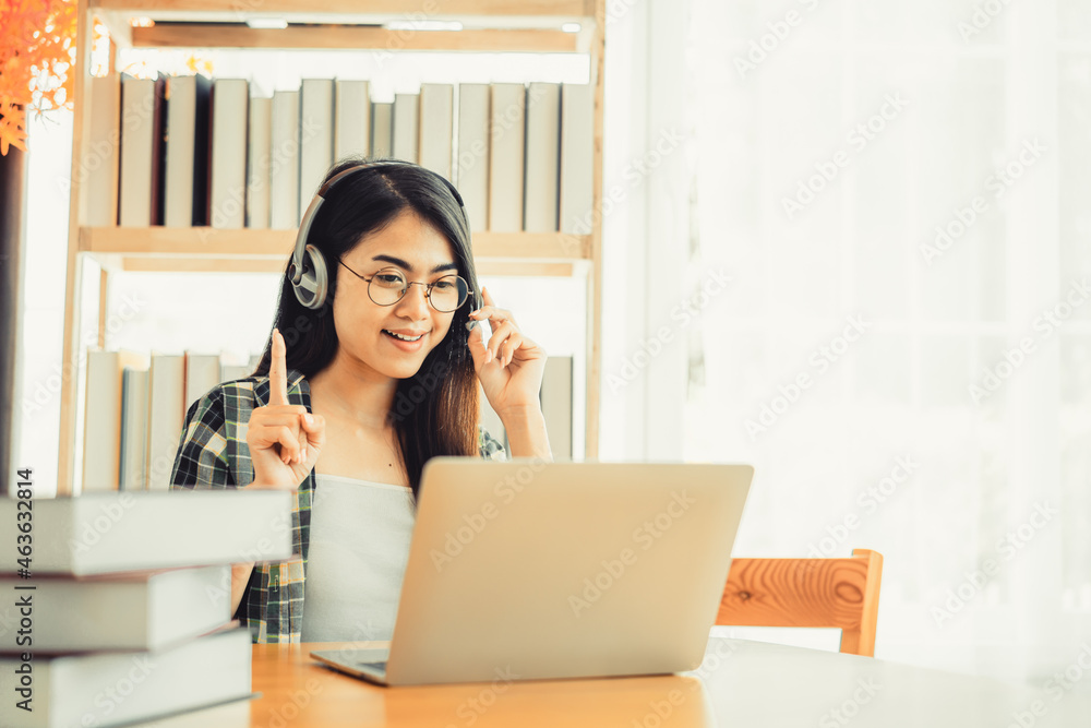 Young female student in plaid shirt sitting at the table using laptop when studying.
