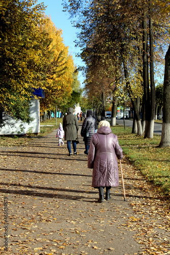 An old grandmother walks along the sidewalk in the city and walks on a sunny autumn day. © Снежана Кудрявцева