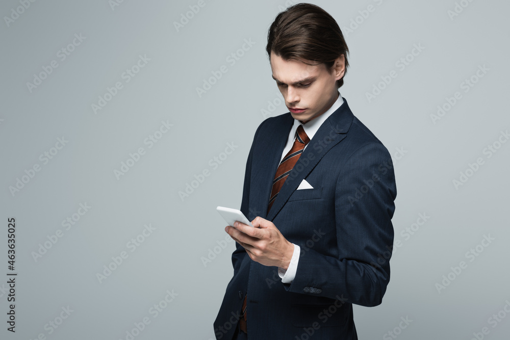 young businessman in suit using smartphone isolated on grey young businessman in suit using smartphone isolated on grey