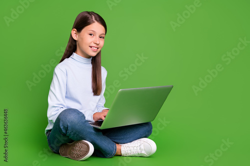 Photo of cute pretty school girl dressed blue turtleneck sitting floor chatting modern gadget empty space isolated green color background