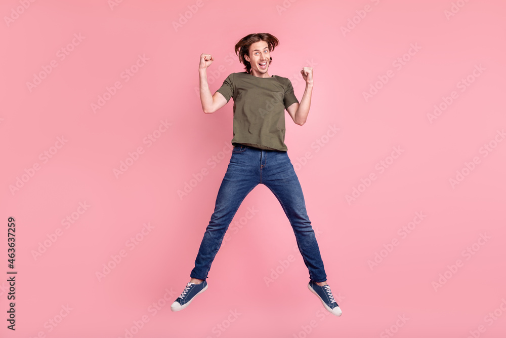 Full size photo of young guy happy positive smile rejoice victory success sale jump isolated over pink color background Full size photo of young guy happy positive smile rejoice victory success sale jump isolated over pink color background