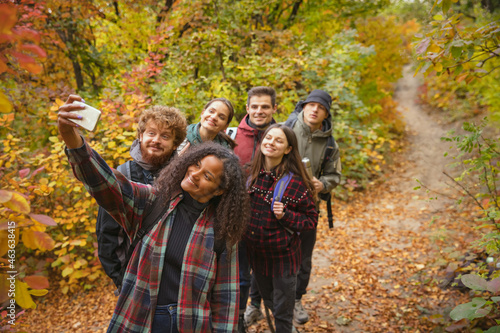 Group of young, joyful friends doing selfie while hiking, spending time togeter in the fores photo