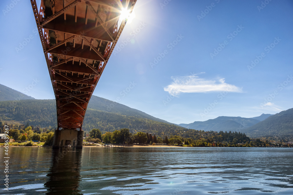 Big Orange Bridge over Kootenay River with Touristic Town in background. Sunny Fall Season Morning. Located in Nelson, British Columbia, Canada.