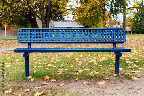 Blue buddy bench in park in autumn season at schoolyard