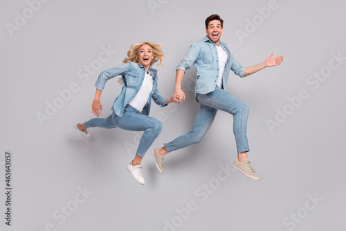 Full length profile side photo of young couple happy positive smile jumper go walk run isolated over grey color background
