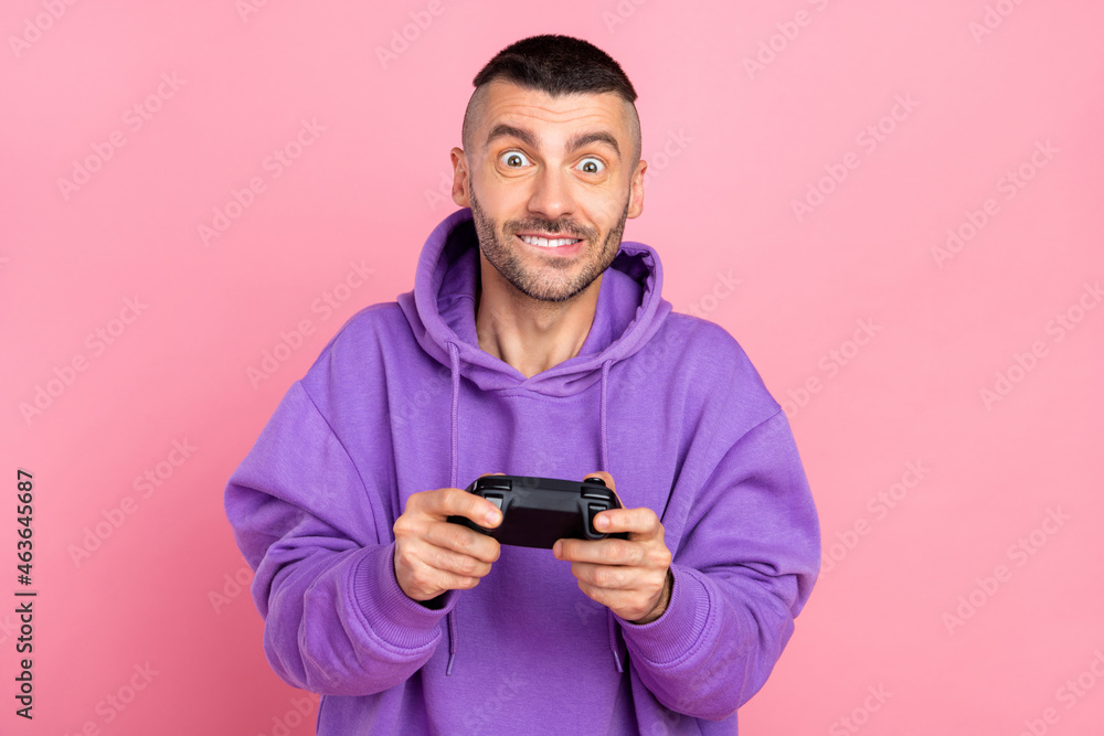 Photo of cute young brunet guy playstation wear violet hoodie isolated on pink background Photo of cute young brunet guy playstation wear violet hoodie isolated on pink background