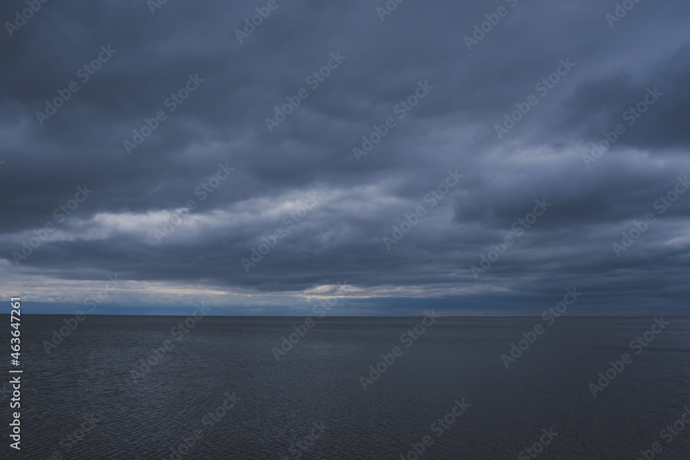Blue dark evening sky with clouds and dark sea background