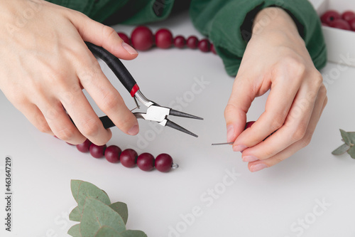 Woman   s hands are locking the wire on a decorative wreath. Close up.