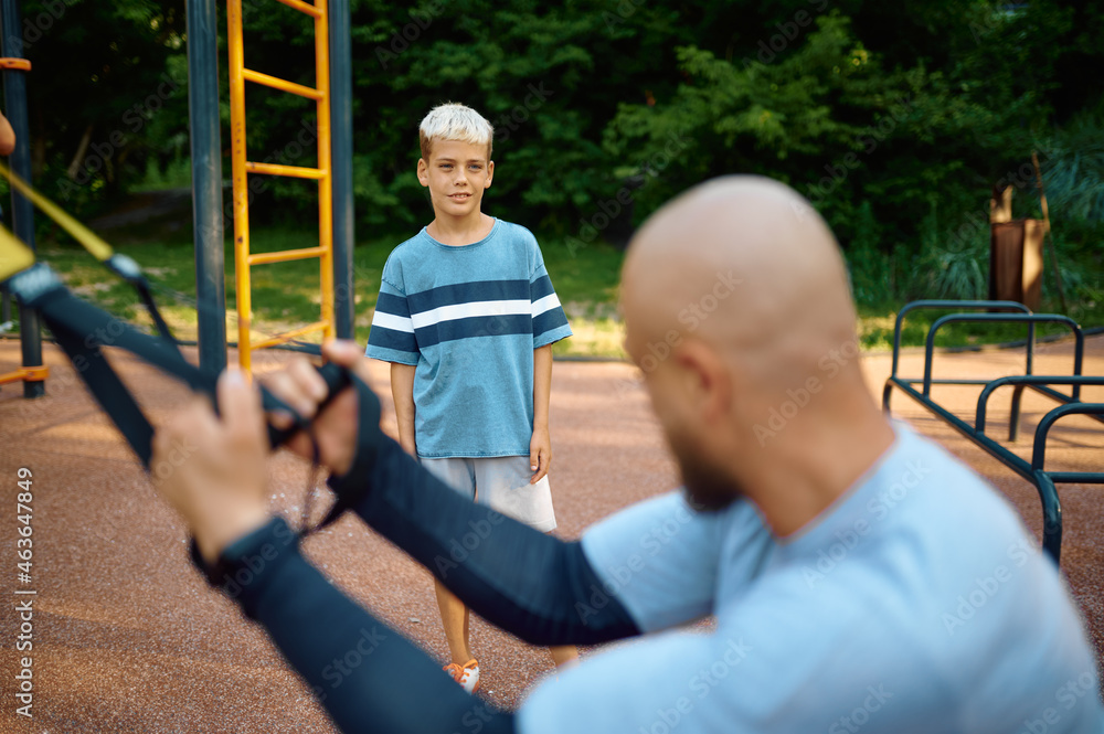 Obraz premium Dad and son doing exercise with ropes, playground