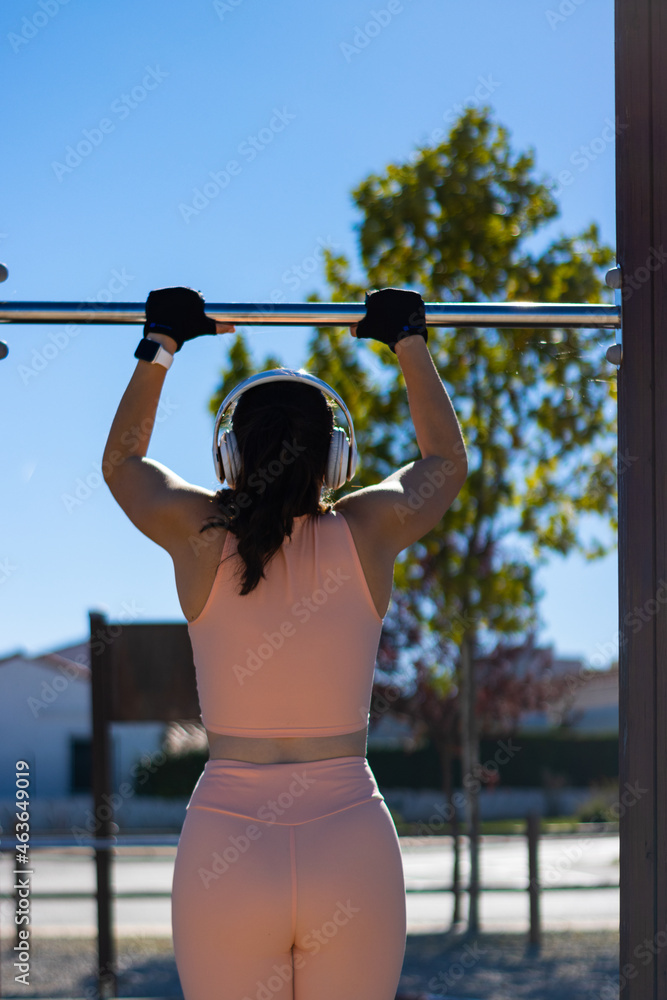 Fototapeta premium young girl doing calisthenics exercise on bars outdoors. pull-up exercise