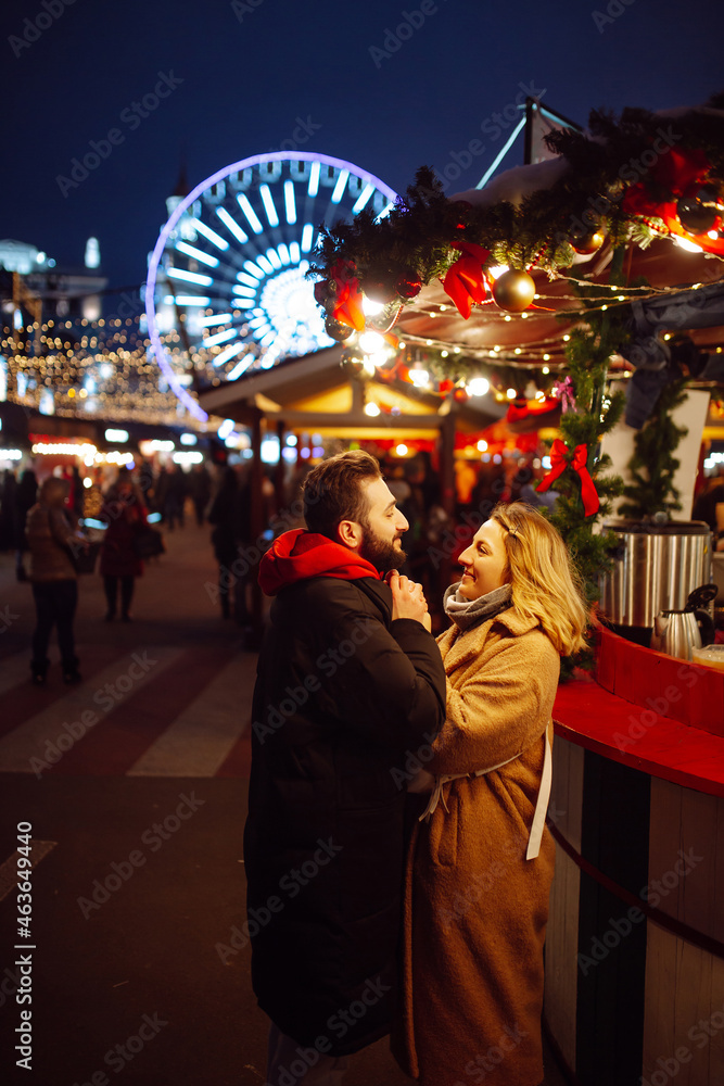 Happy couple of tourists in warm clothes walking at the christmas market. Holidays, winter, christmas, new year, travel concept. 