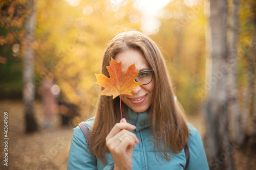 Autumn portrait of beautiful woman with maple leaves on fall nature background