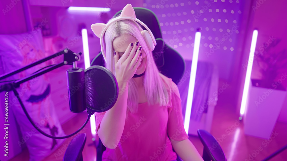 Amused cute gamer girl with cat ear headphones face palm while streaming Amused cute gamer girl with cat ear headphones face palm while streaming