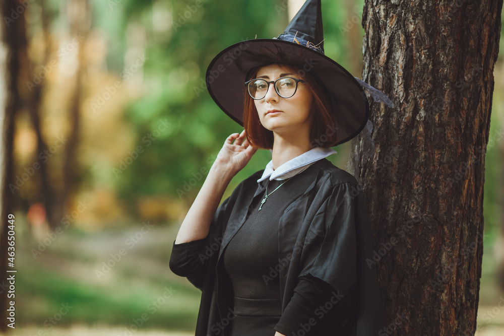 Halloween Witch. Portrait of a girl in a hat and a witch costume in the forest. Ready for trick or treat holiday