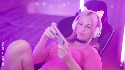 Cute Blonde Gamer Girl on Gaming Chair playing Games on Smartphone