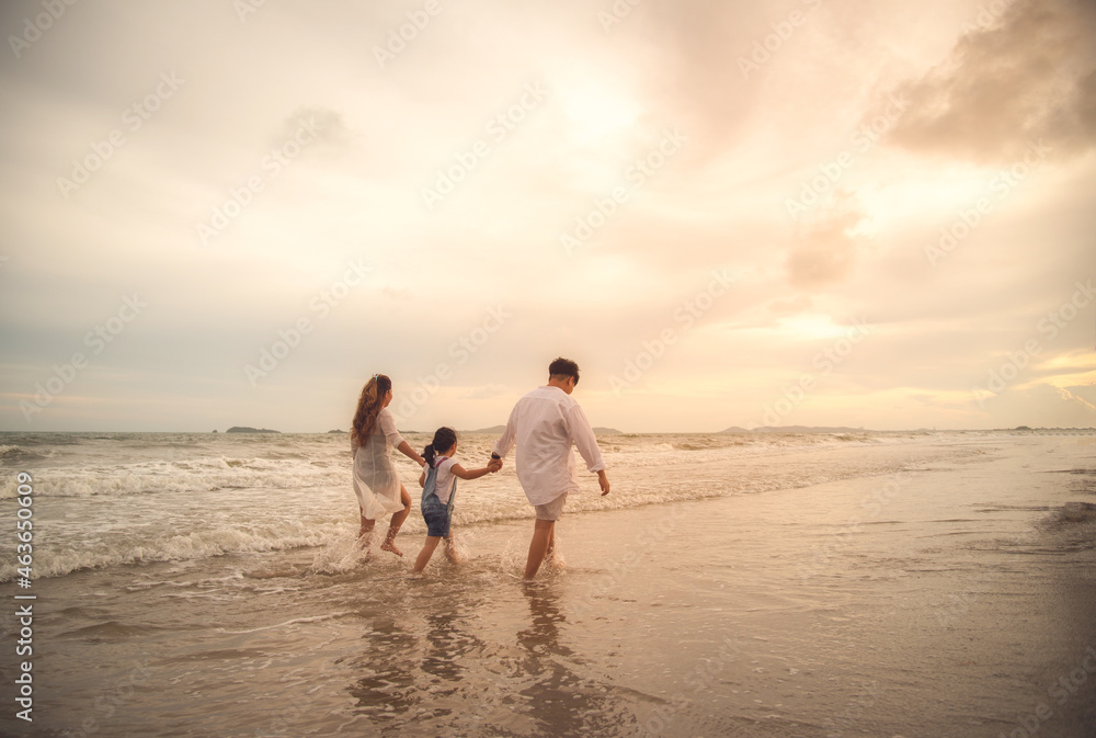 Happy family on the beach against blue sea and sky background at sunset. Holiday and summer travel concept