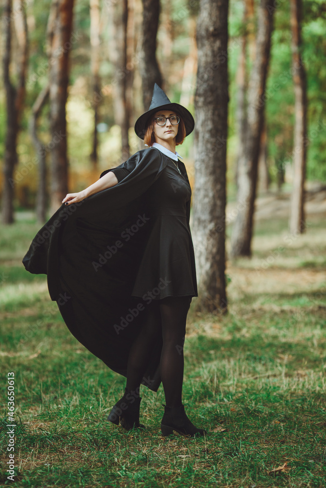 Halloween Witch. Portrait of a girl in a hat and a witch costume in the forest. Ready for trick or treat holiday