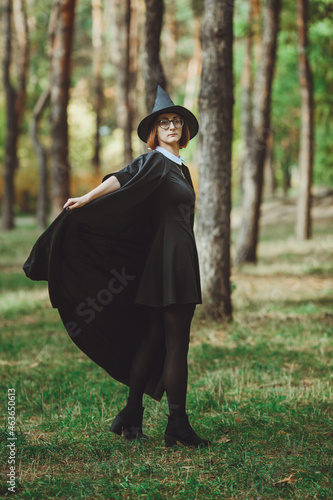 Obraz na płótnie Halloween Witch. Portrait of a girl in a hat and a witch costume in the forest. Ready for trick or treat holiday
w salonie