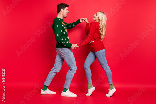 Full length body size photo people laughing in ugly jumpers dancing holding hands isolated vivid red color background