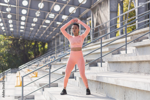 Woman doing burpee exercise, young African American woman doing fitness and active lifestyle in the morning, outdoors near the stadium photo