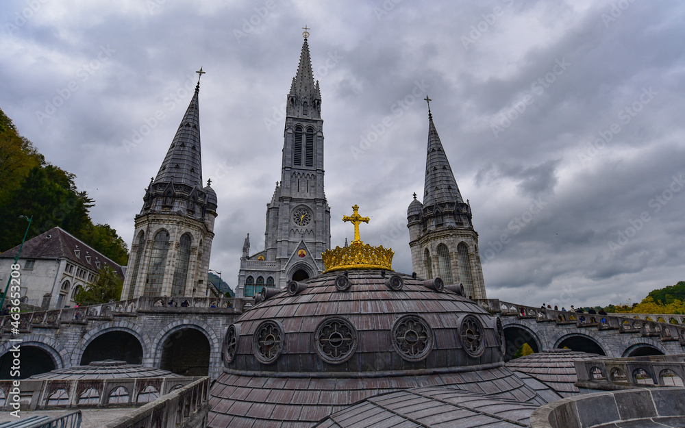 Lourdes, France - 9 Oct 2021: Gold gilded cross atop the dome of the Basilica of Our Lady of the Rosary in Lourdes