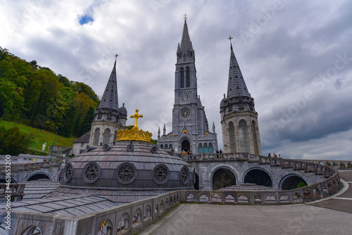 Lourdes, France - 9 Oct 2021: Gold gilded cross atop the dome of the Basilica of Our Lady of the Rosary in Lourdes