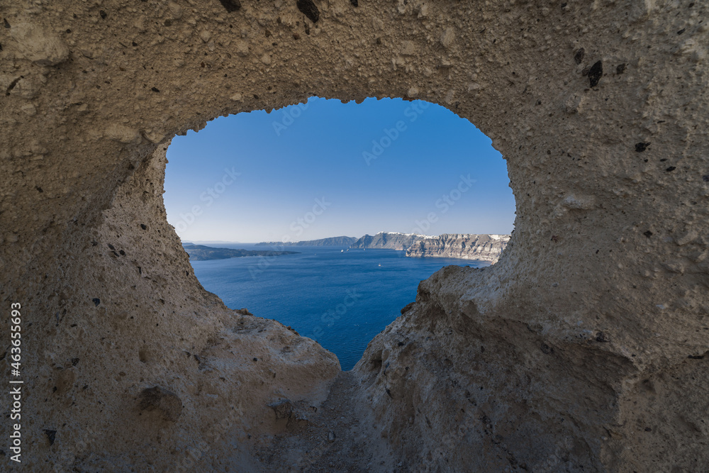 View of the Aegean Sea and village of Santorini Island from a cave hole, Greece