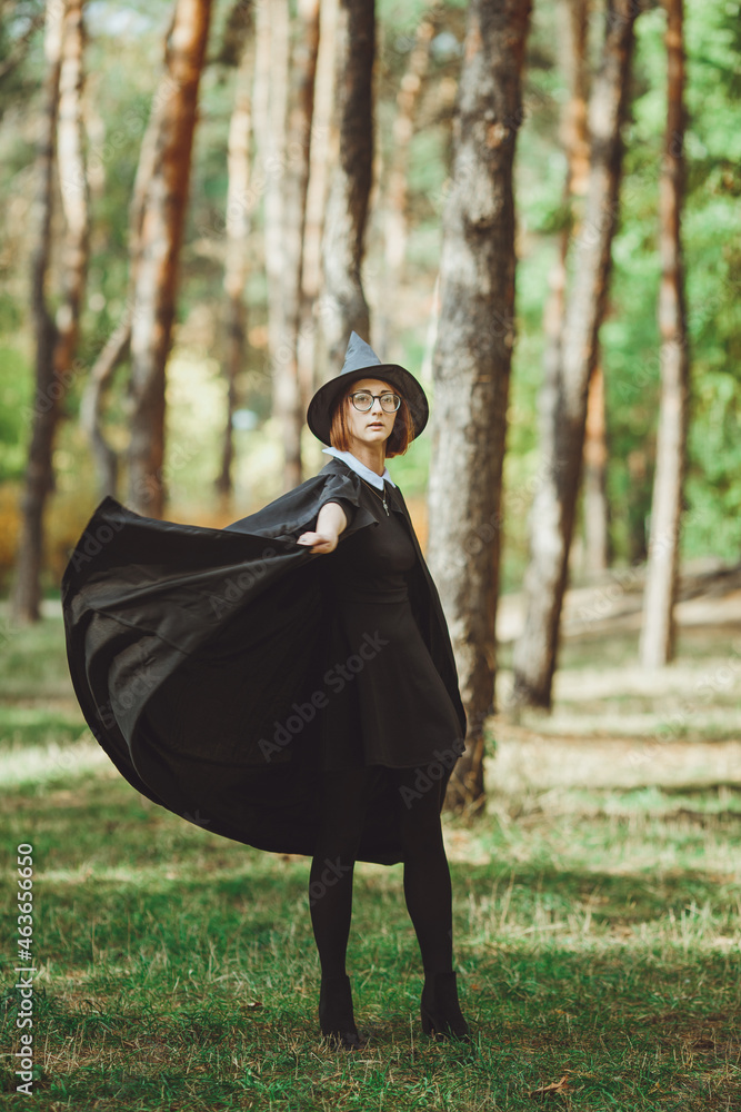 Halloween Witch. Portrait of a girl in a hat and a witch costume in the forest. Ready for trick or treat holiday