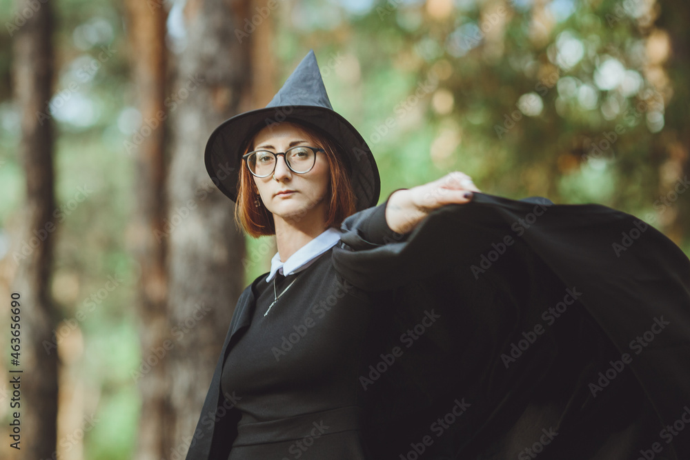 Halloween Witch. Portrait of a girl in a hat and a witch costume in the forest. Ready for trick or treat holiday