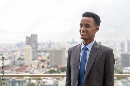 Portrait of handsome African businessman wearing suit and tie at rooftop in city