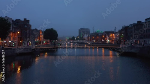 Wallpaper Mural Pedestrians walking on footbridge across river in evening city. Ascending footage of town after sunset. Dublin, Ireland Torontodigital.ca