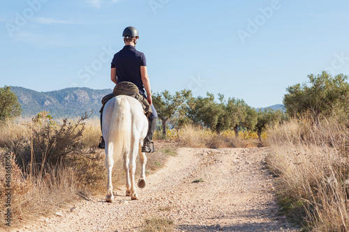 A horseman riding as seen from his back photo