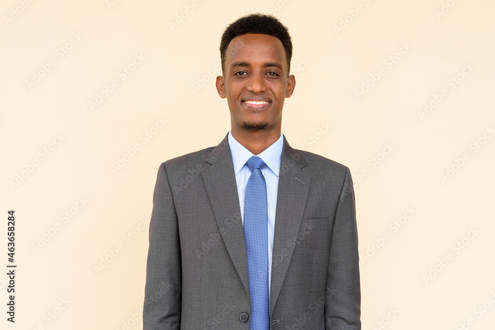 Portrait of handsome African businessman smiling and wearing suit and tie against plain background Portrait of handsome African businessman smiling and wearing suit and tie against plain background