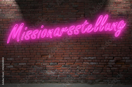 Neon missionary position (in german Missionarsstellung) lettering on Brick Wall at night photo