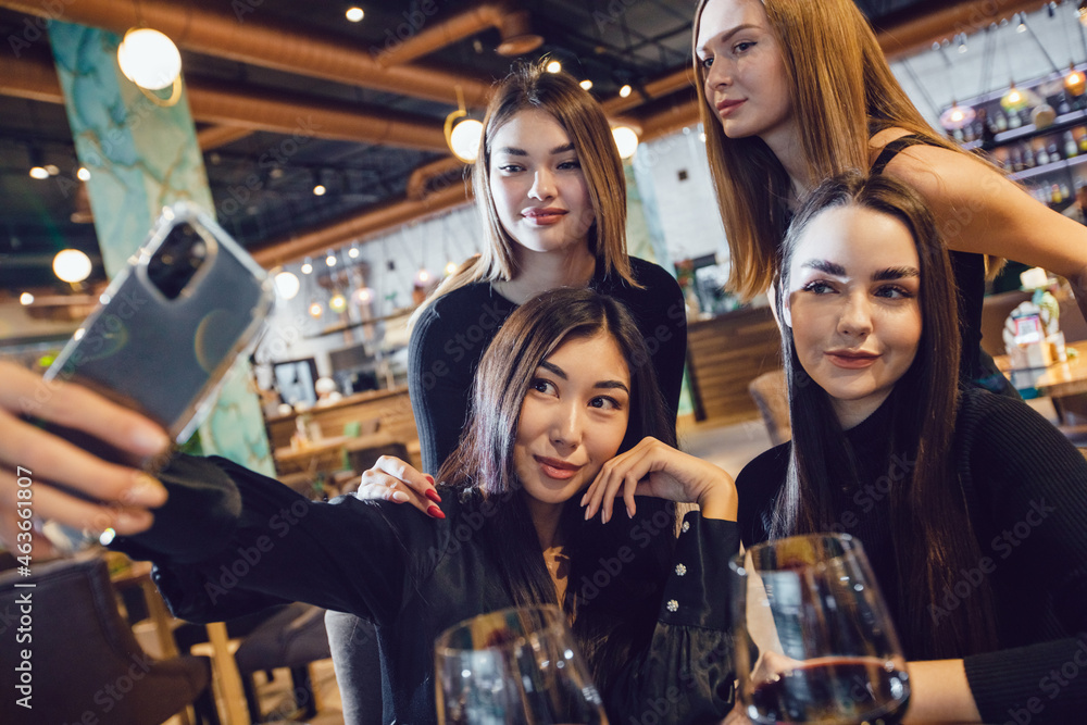 A group of girlfriends take a selfie at dinner in a restaurant.