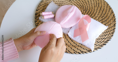 Close-up hand asia woman help make craft pink single fill up bra cup insert for post mastectomy prosthesis surgery MRM at home. Relief work service support give hope to tumor patient medical issue.