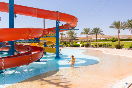 Hurghada, Red Sea Governorate, Egypt 17.09.2021: little girl stands in the middle of the pool of the water park near the colored water slides