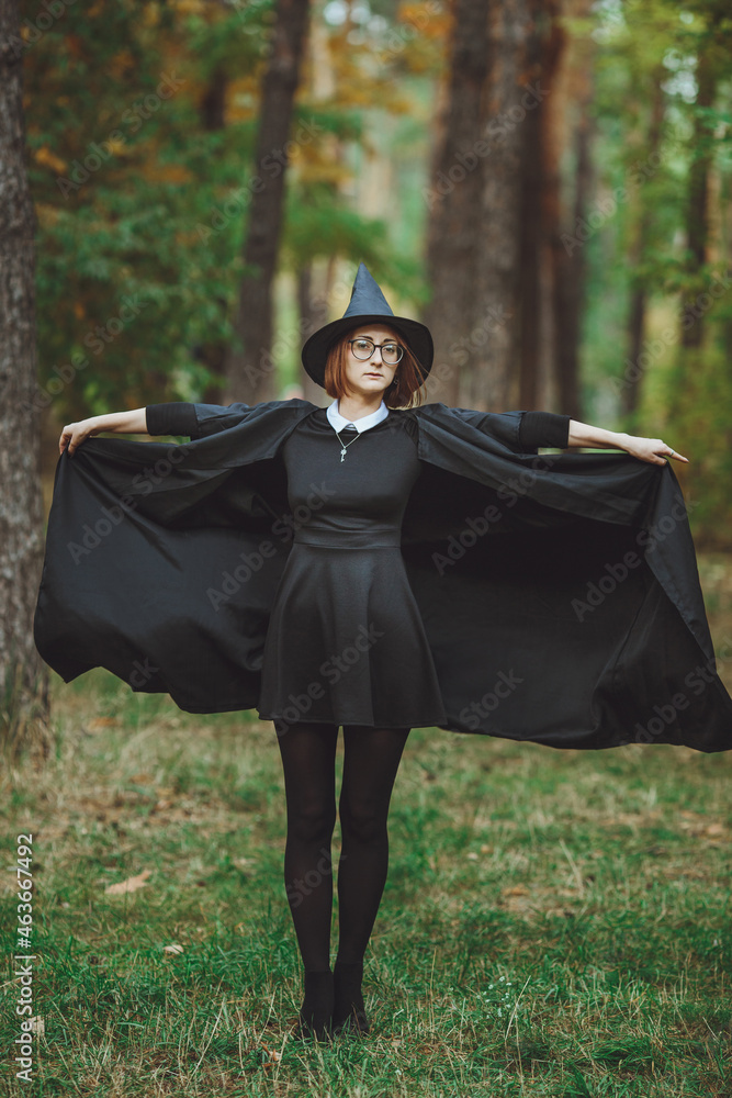 Halloween Witch. Portrait of a girl in a hat and a witch costume in the forest. Ready for trick or treat holiday