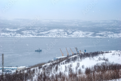 Harsh north. Winter landscape. Snow flakes cover the hills of the Kola Peninsula and the water of the Kola Bay. Murmansk.